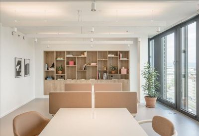 Communal breakout area featuring a large wooden bookshelf and dining table.