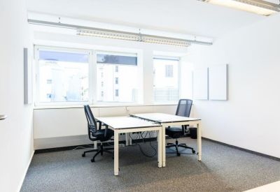 Bright two-person private office with white desks and large windows.