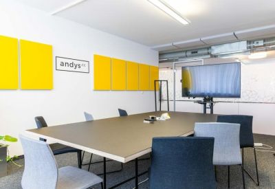 Professional meeting room with a large table, grey chairs, and yellow acoustic panels.