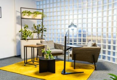Cozy breakout area with a yellow rug, armchairs, and glass block wall.