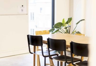 Professional meeting room with a wooden table, black cantilever chairs, and a large window.