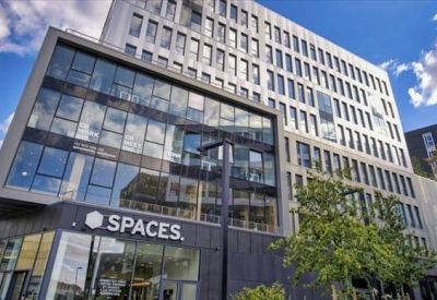 Bright coworking area with individual workstations and a tall acoustic privacy screen.