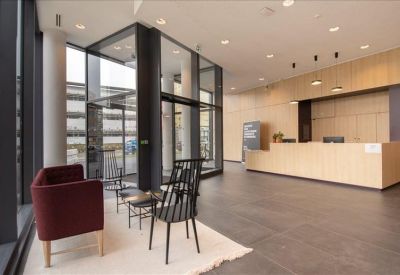 Modern reception lobby with a light wood desk and stylish black spindle chairs.