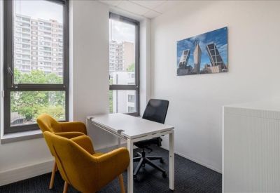 Private office featuring a white desk and two mustard yellow velvet armchairs by a window.