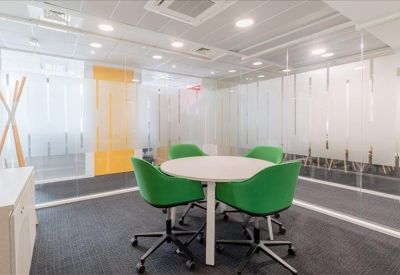 Small meeting area with a round white table and four bright green chairs.