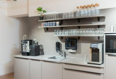 Sleek office kitchen with coffee machines and open shelving for glassware.