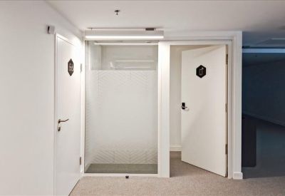 Bright white corridor featuring private office doors and frosted glass partitions.