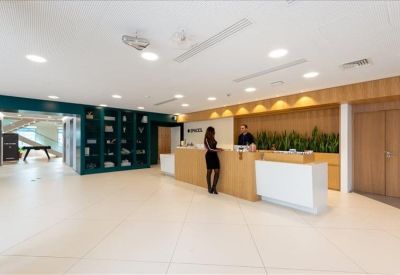 Modern reception area with a wooden front desk, professional staff, and indoor greenery.
