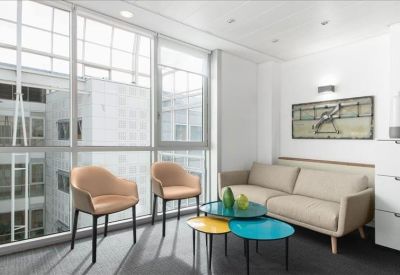 Modern lounge area with colorful coffee tables, light wood chairs, and a large window.