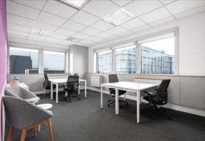 Bright four-person office suite with white desks and a purple feature wall.