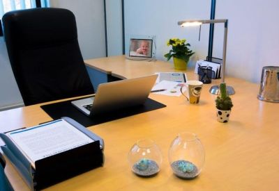 Modern workstation with a laptop, document tray, desk lamp, and small decorative plants.
