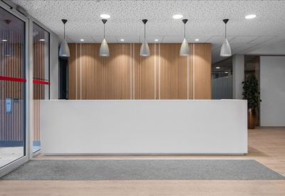 Minimalist white reception desk with wood-paneled background and pendant lights.
