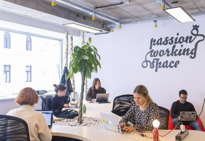 Modern coworking area with a curved white desk, indoor tree, and wall art reading passion working space.