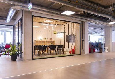 Glass-walled meeting room with a long table, black chairs, and a decorative birch tree feature.