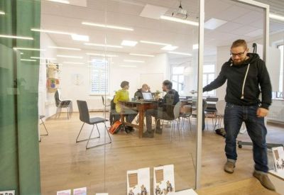 Glass-walled meeting area with a group working at a central table.