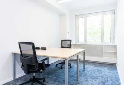 Bright private office suite with two workstations and a large window overlooking trees.