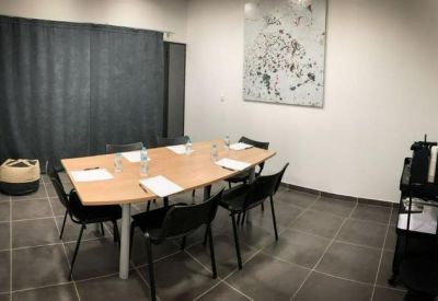 Small private meeting room with a wooden table, black chairs, and abstract wall art.