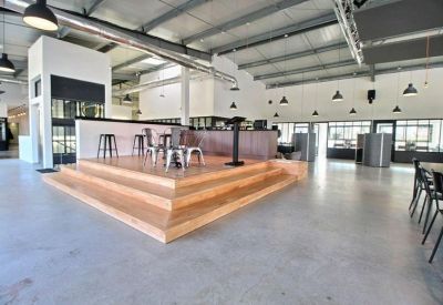Spacious communal event space with tiered wooden seating and industrial ceilings.