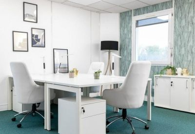 Bright three-person office suite with white desks and teal carpeting.
