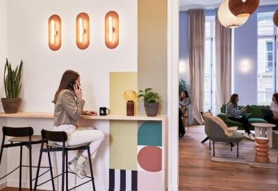 Professional reception or breakout area with a coffee bar, stools and stylish wall lighting.