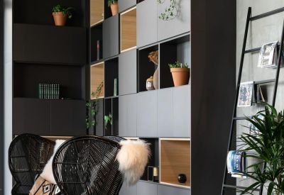 Cozy lounge area with a modular grey storage wall and a stylish black chair.