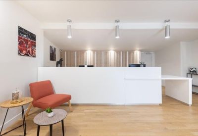 Clean white reception area with an orange lounge chair and modern lighting.