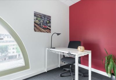 Private office featuring a white desk, ergonomic chair, and red accent wall.