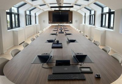 Long formal boardroom table under a vaulted ceiling with skylights.