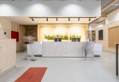 Minimalist reception desk made of light wood with track lighting above.
