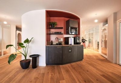 Sleek coffee station within a curved white wall unit and dark cabinetry.