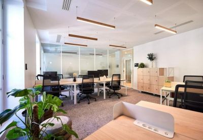 Open-plan workspace with multiple desks, ergonomic chairs, and large windows.