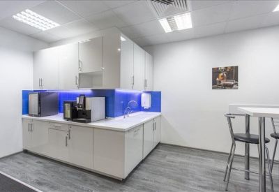 Modern kitchen and breakout area with blue backlighting and coffee machines.