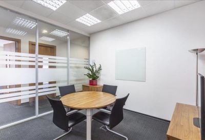 Compact meeting room with a round wooden table and glass partitions.
