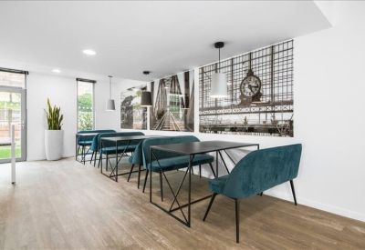 Communal dining area with teal benches and large black and white city murals.