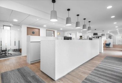 Clean white reception desk illuminated by a row of gray pendant lights.