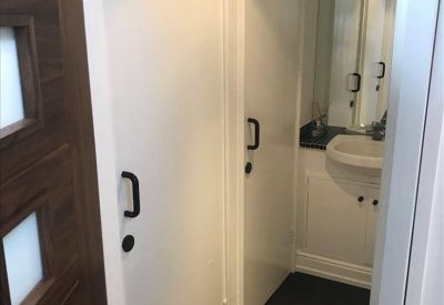 Modern bathroom area with white doors and dark wood flooring.