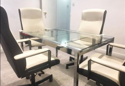 Modern glass meeting table with four white and black executive chairs.