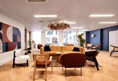 Spacious communal lounge featuring a yellow velvet sofa, modern armchairs, and a large dried floral ceiling fixture.
