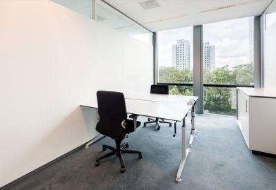Minimalist private office with white desks, black chairs, and a view of the city through floor-to-ceiling windows.