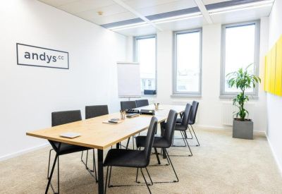 Spacious wood-topped conference table in a bright meeting room with the andys.cc logo on the wall.