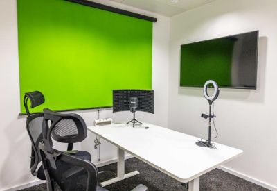Professional recording studio equipped with a green screen, ring light, and podcast microphone.