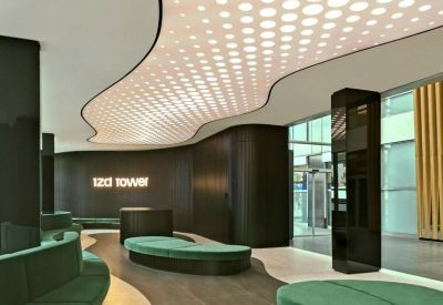 Stylish lounge with a wavy patterned light ceiling and green velvet curved sofas.