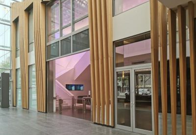 Modern building lobby featuring light wood panelling and a glass entrance door.