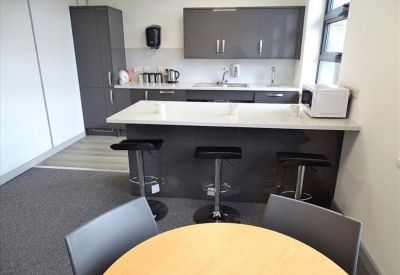 Contemporary communal kitchen and breakout area with breakfast bar and stools.