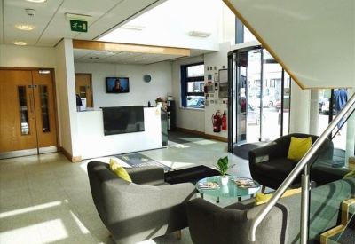 Bright reception area with soft seating, coffee table, and revolving door entrance.