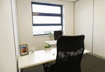 Single person private office suite with white desk and black ergonomic chair.