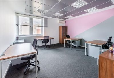 Spacious private office with four desks and a pink feature wall.