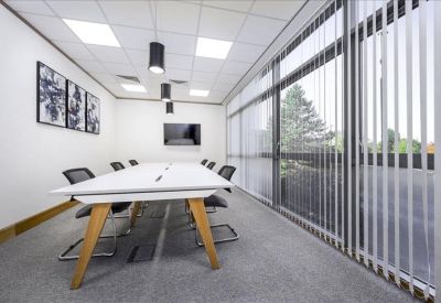 Modern breakout area featuring blue upholstered booths, white tables, and a large potted plant.