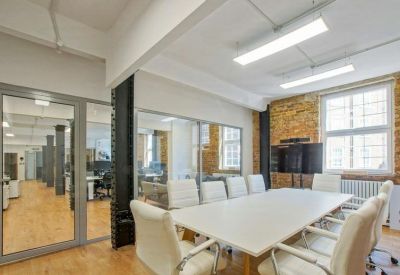 Professional meeting room featuring a long white table and exposed brick wall.