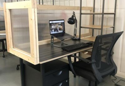 Dedicated workstation with a black desk, ergonomic chair, and privacy screen.